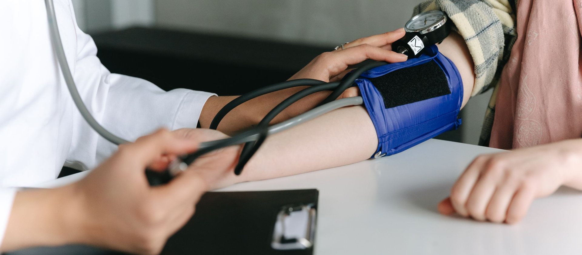 A clinician taking a blood pressure reading with a cuff and stethoscope