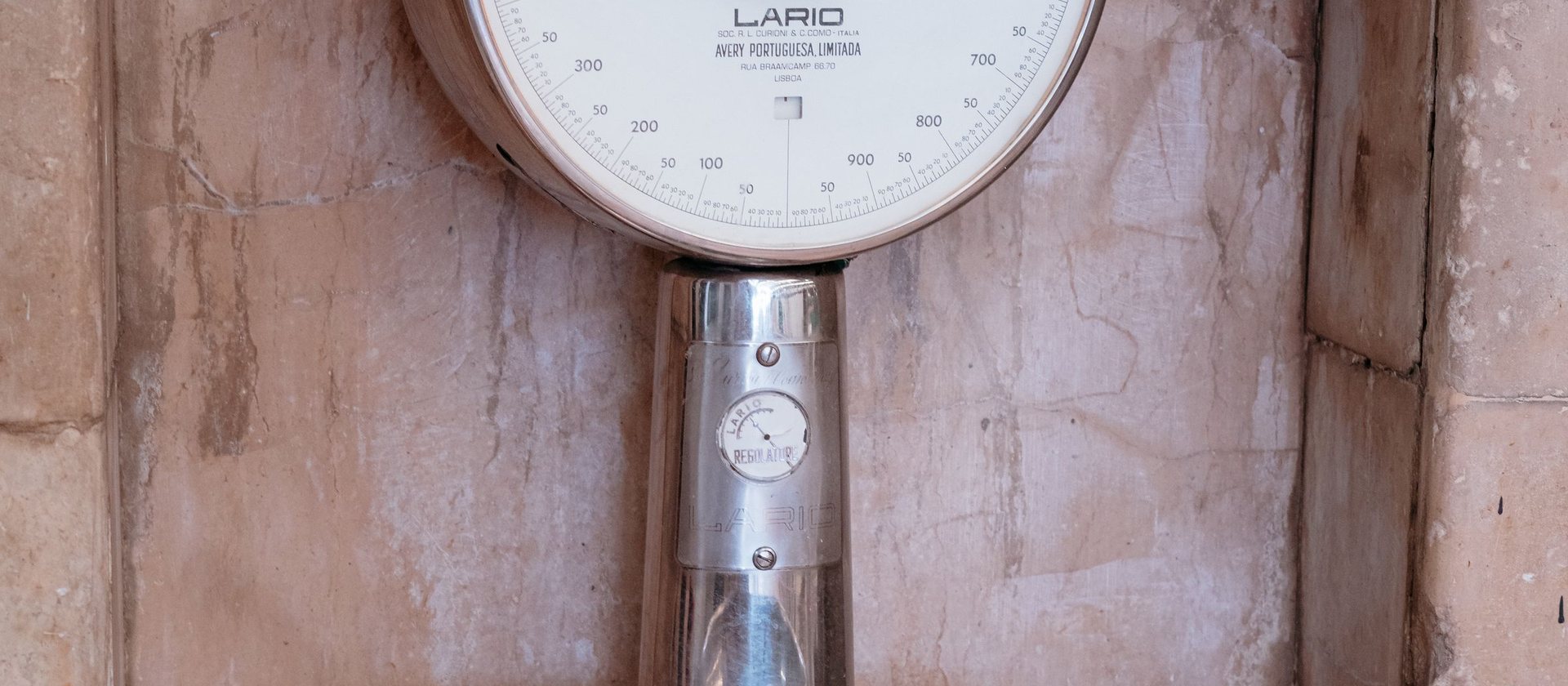 A weighing scale mounted on a pink plaster wall