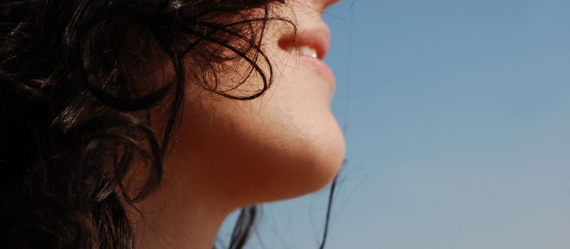 A person's throat and neck in profile, chin lifted to an open sky