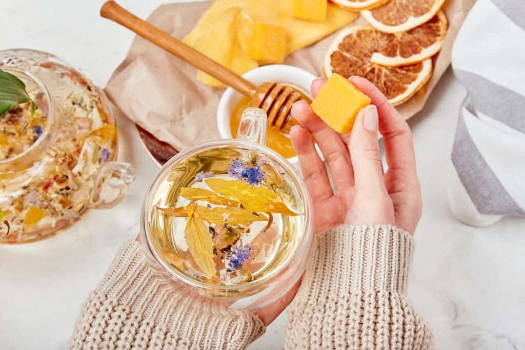 Woman add honey to organic mountain blend - calming herbal elixir